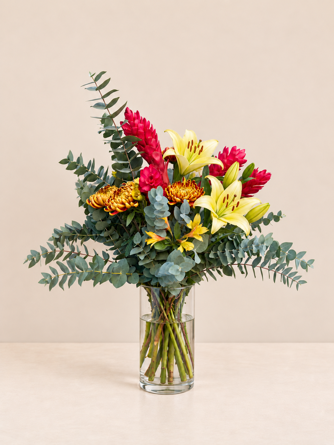 Arranjo do Dia com lírios amarelos e flores vermelhas em vaso de vidro, tamanho M